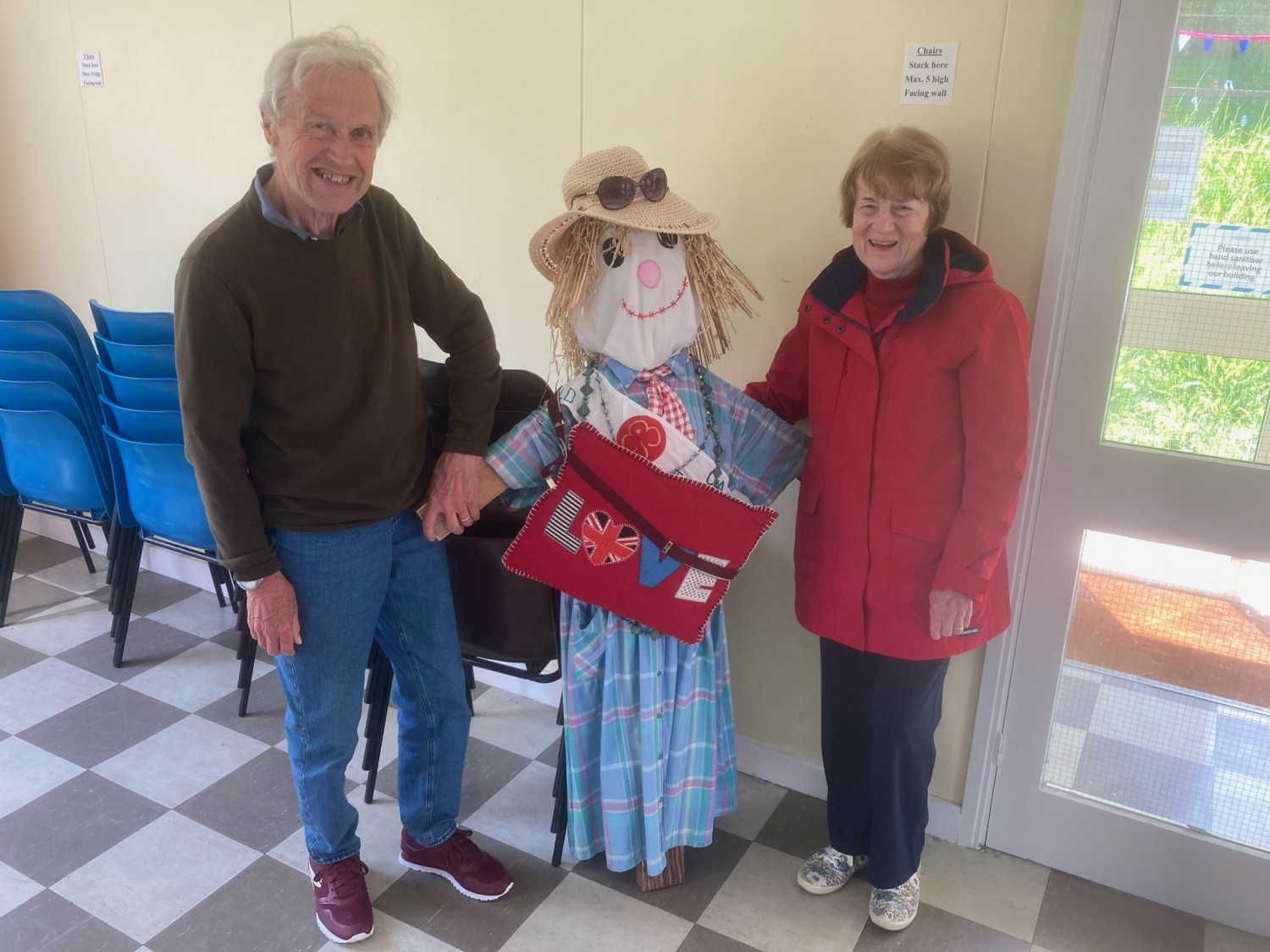 Scarecrow relaxes in church hall with friends.